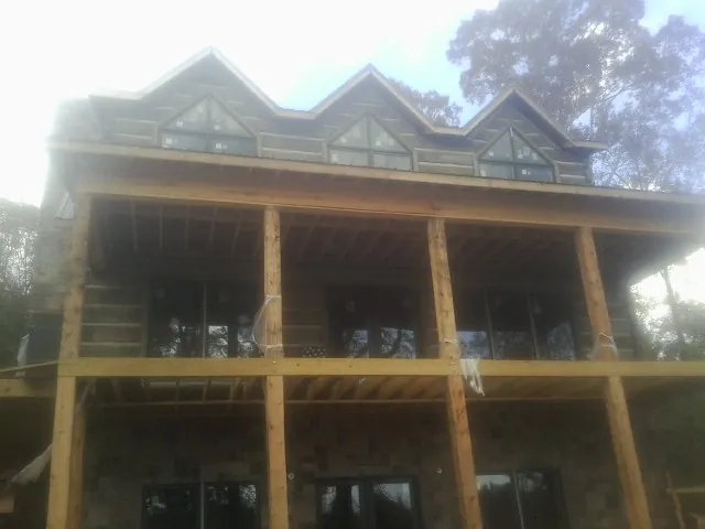 Dormers and porch framing on a large log home under construction — Roof Coating work by our crew in Westbury