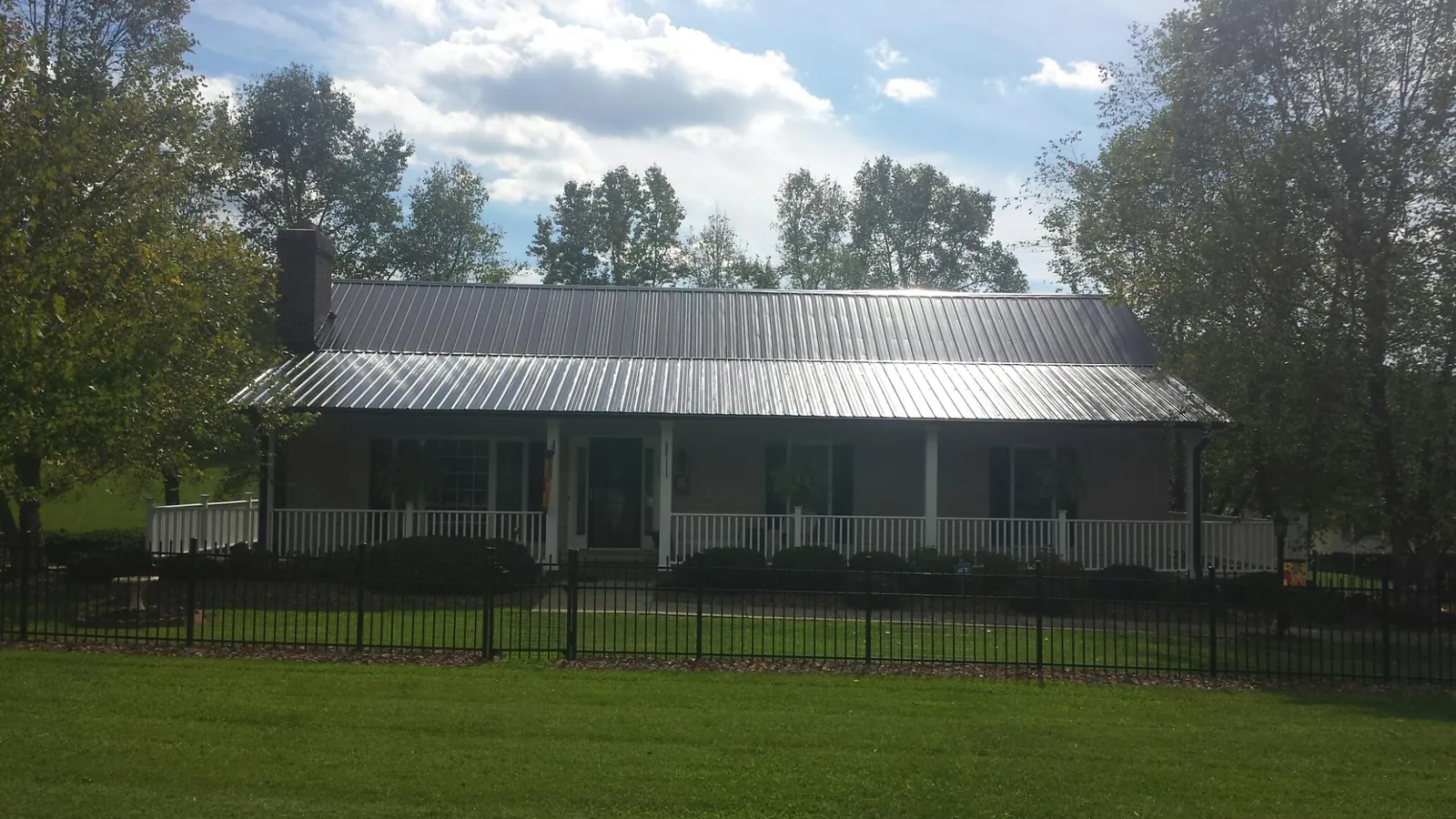 Gray metal roof on a brick ranch with a full width front porch — Gutter Guard Installation work by our crew in Westbury