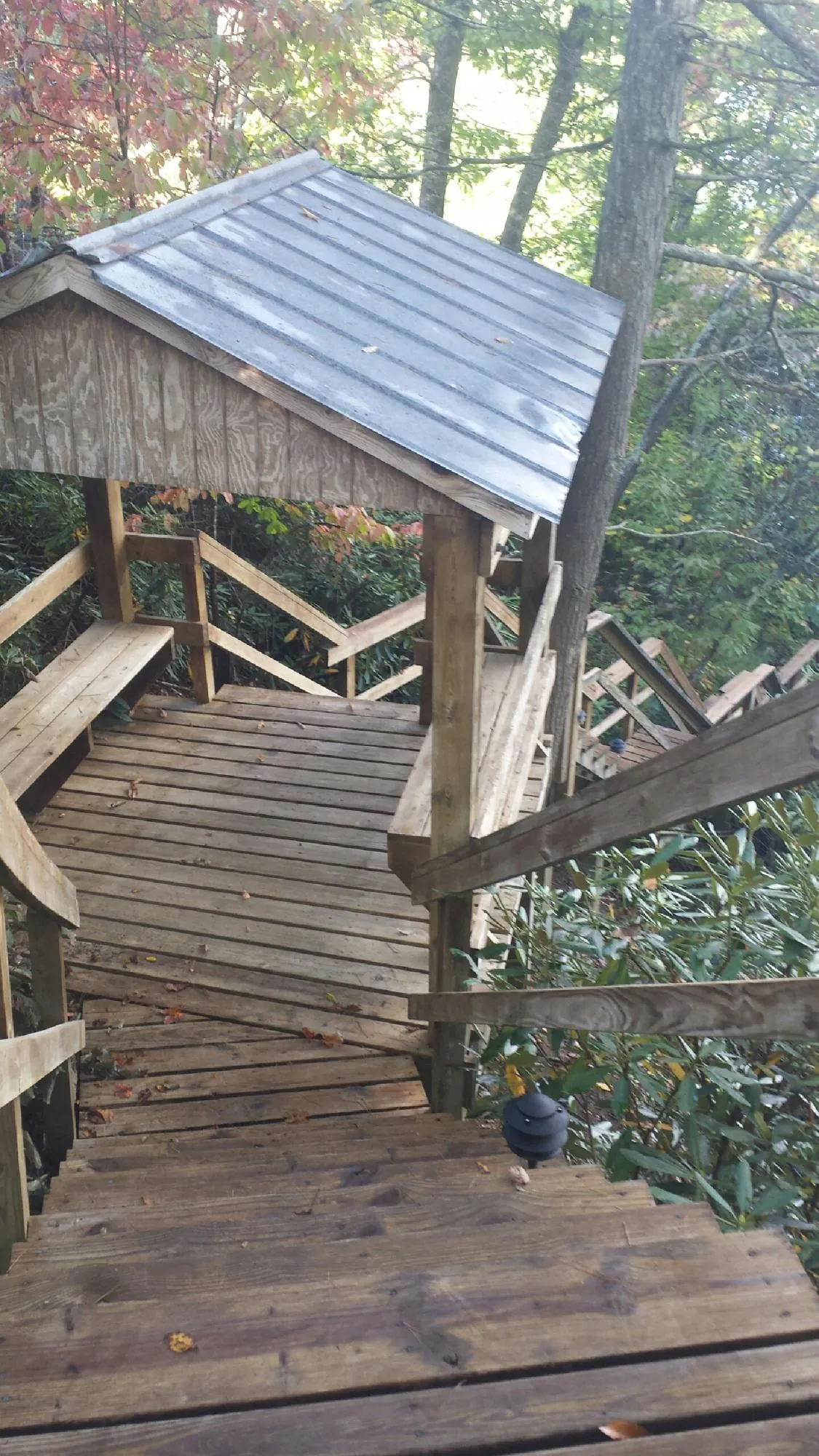 Metal roofed shelter over wooden steps on a wooded walkway — Skylight Repair & Installation work by our crew in Westbury
