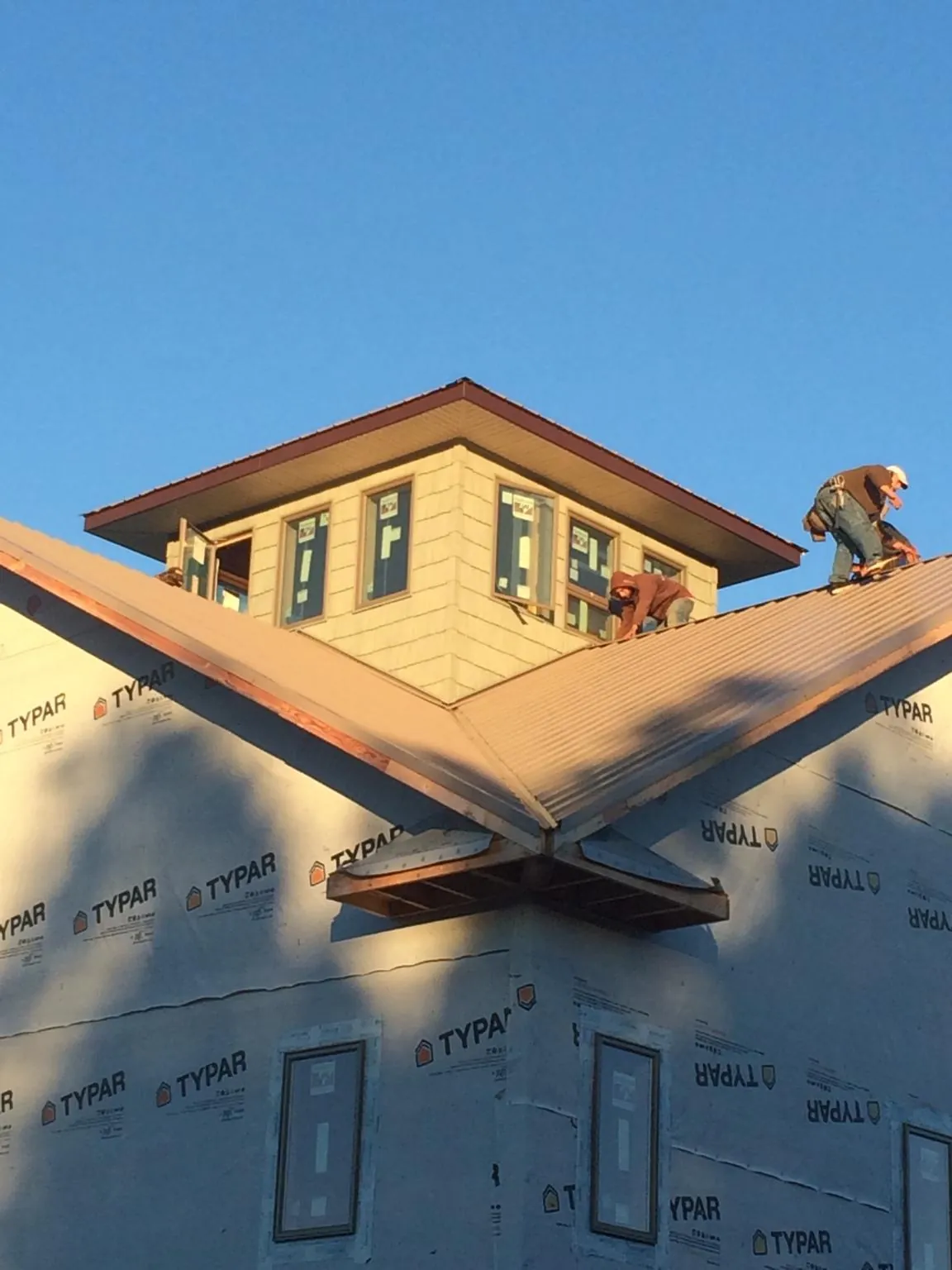 Roofers working around a rooftop cupola on a new metal roof at sunset — Roof Waterproofing in Westbury by Roofing Brothers